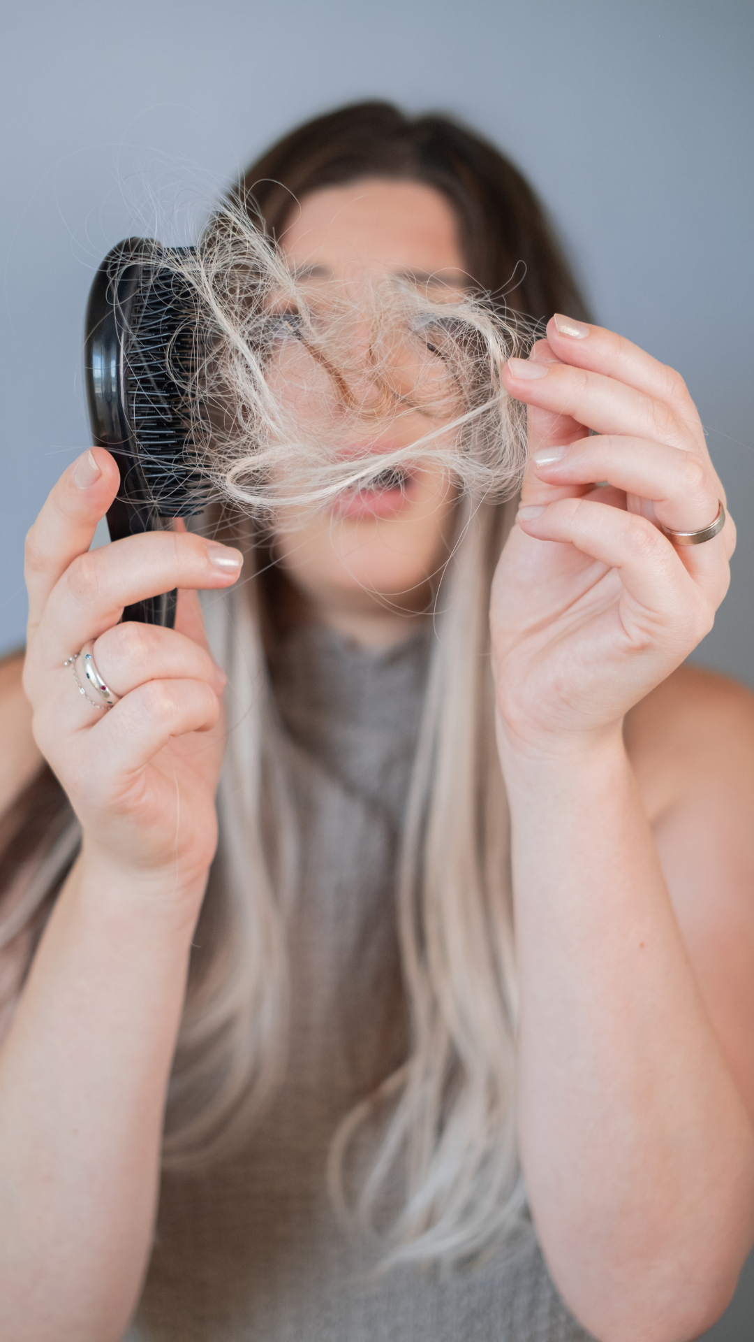 Mujer mostrando caída del cabello con mechón en mano